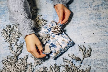 Kız Noel için el yapımı Xmas Blue hediye paketini kumaş thuja ve koni ile hazırlıyor. Geleneksel Japon furoshiki tarzında sıfır ziyan hediyesi. Ekolojik konsept çevre dostu dekor xmas.