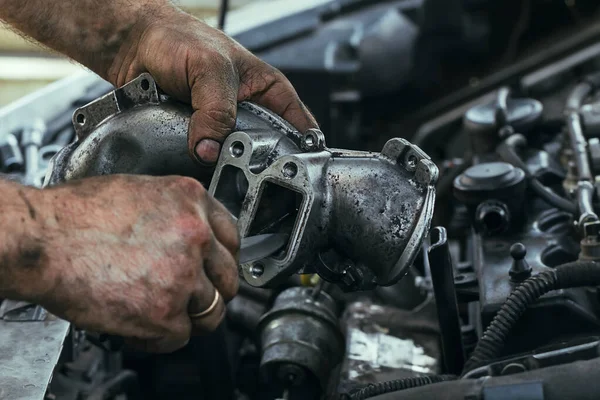 Брудні, жирні руки чоловіка, який ремонтує двигун, EGR клапан, крупним планом Ліцензійні Стокові Зображення