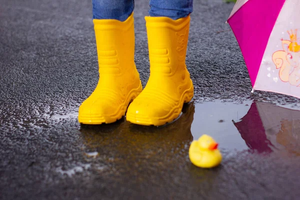 Rubber yellow boots stand in a puddle next to lies a yellow rubber duckling. bad weather . High quality photo