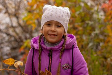 Sonbaharda mor ceketli ve beyaz şapkalı güzel bir kızın portresi. Elinde portakal yapraklı bir kavak dalı tutuyor.