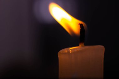 Yanan bir balmumu beyaz mumun koyu arkaplandaki makro fotoğrafçılığı. Yüksek kalite fotoğraf