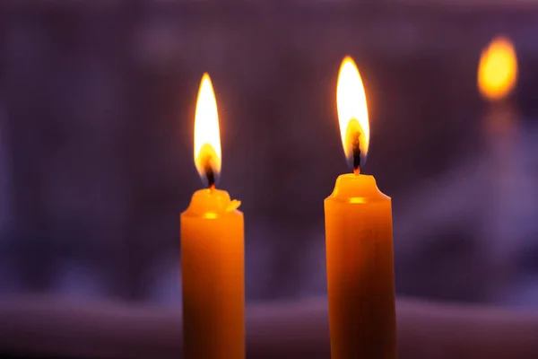 Two candles are lit on a dark background. Macro photography. High quality photo