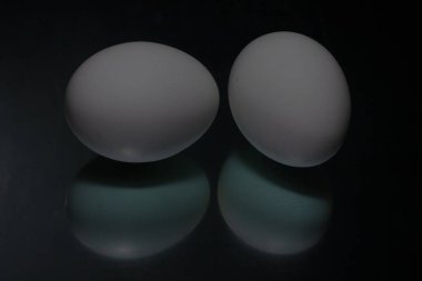 Siyah arka plana iki beyaz yumurta yansıtılır. Yüksek kalite fotoğraf