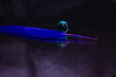 Mavi tüy cam bir topun yanında yatıyor. Yüksek kalite fotoğraf