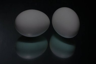 Siyah arka plana iki beyaz yumurta yansıtılır. Yüksek kalite fotoğraf