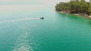 Didim, Türkiye 'deki Akbuk Körfezi' nde mavi Ege Denizi ile çevrili bir sürat teknesini takip eden insansız hava aracı