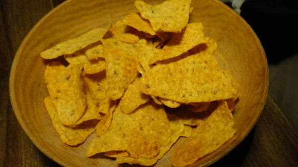 Mexican nachos chips in a bowl. Tortilla or Nacho Chips for snack. Close-up view of Mexican Corn Chips Nachos on wooden background.