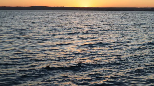 Orange gold sunset on sea surface. Sun reflection on water. Landscape under colorful sky at sunset. Orange sundown reflecting from calm Aegean sea at golden hours.