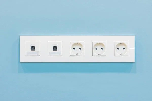 Power socket and Internet socket on blue wall background.