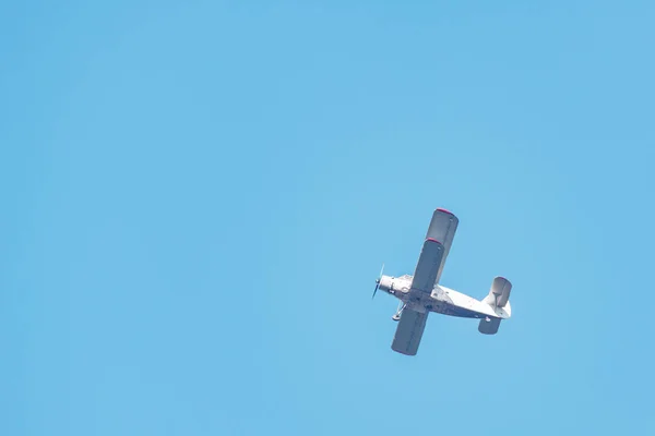 Old retro plane flies in the blue sky.