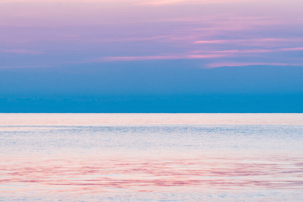 Pink sunset sky above the ocean surface.