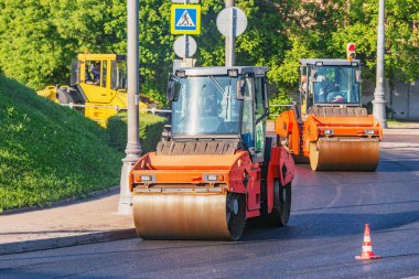 Yol silindirleri yeni yol yapım sürecinde asfalt yüzeyde hareket ederler.