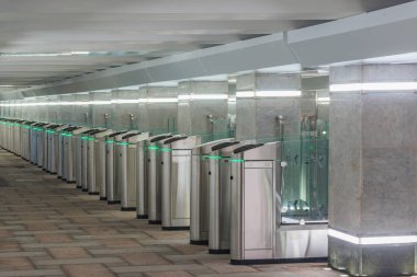 İstasyon platformunda elektronik kart okuyucuları olan turnikeler.