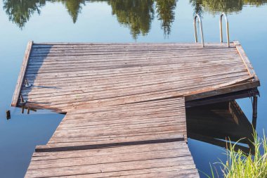 Orman gölü yüzeyindeki küçük ahşap iskele..