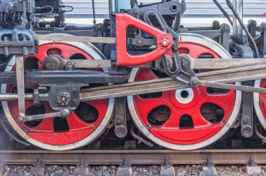Platformun yanında duran eski buhar treninin tekerlekleri.