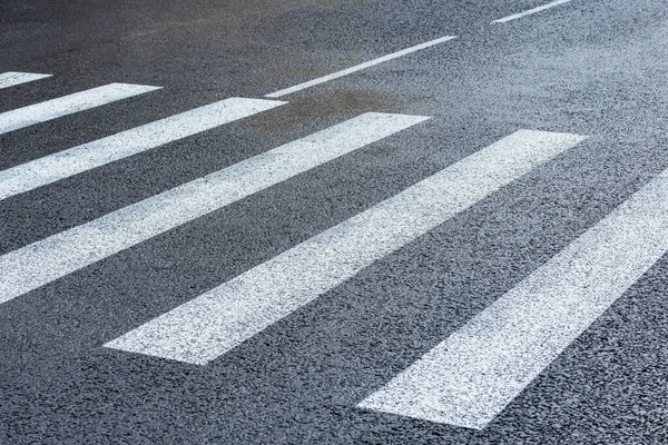 White lines on the city asphalt crossroad.