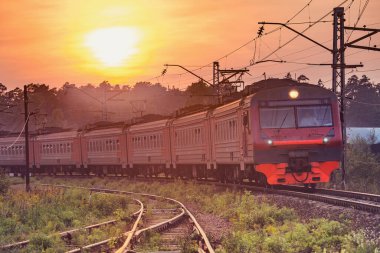 Banliyö treni gün batımında istasyona varır..