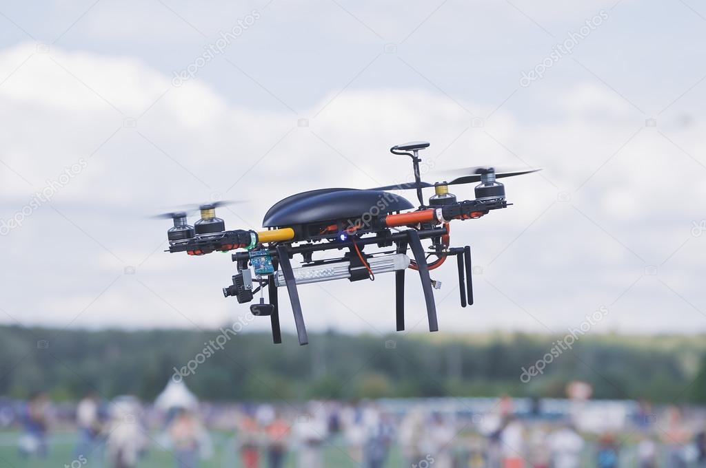 Black quadrocopter above the crowd of people.