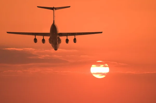 Flight of the cargo plane on the sunset background.