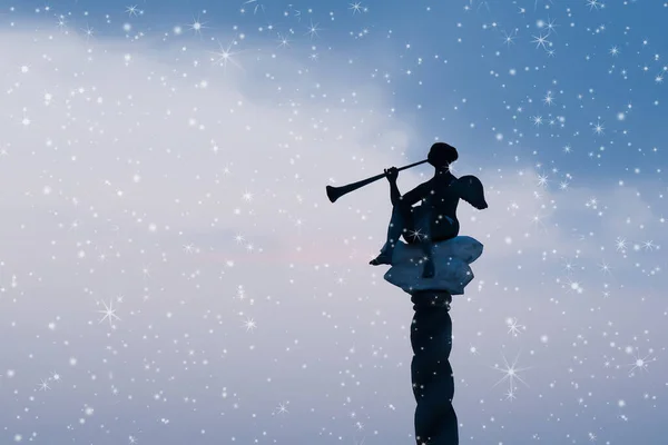 Silhouette of christmas angel on dark blue evening sky. Defocused photo as background for your design