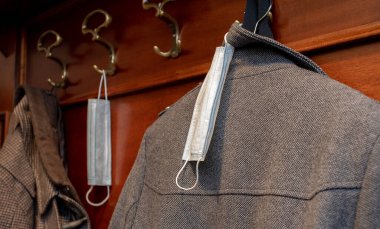 Yeni kural. Koridordaki ceketin yanındaki askıda tek kullanımlık tıbbi maskeler var. Coronavirüs salgını sırasında davranış kuralları.