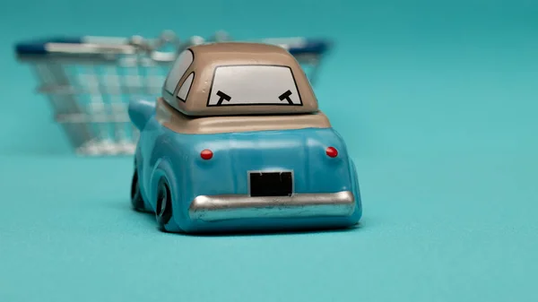 In-store Pickup. Toy car and shopping cart on blue background. Selective focus, copy space of your design. The concept of self-delivery of goods from the store during the outbreak of coronavirus.
