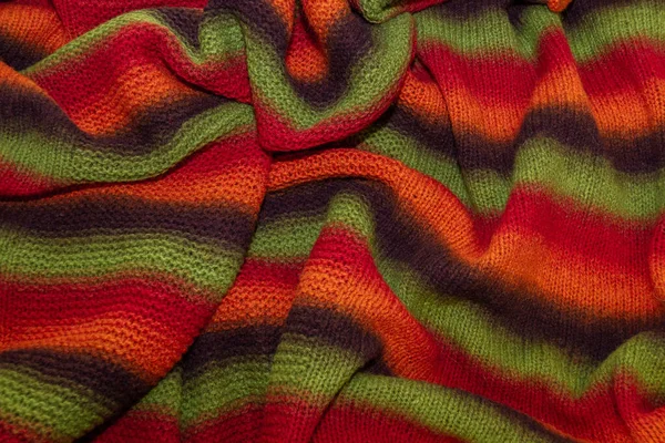Large handmade merino wool blanket, super chunky yarn, fashion concept. Close-up of a knitted designer blanket in red, green and brown wool. Selective focus
