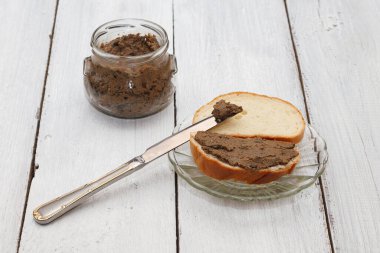 Kuru erikli tavuk ciğeri ezmesi ve beyaz ahşap arka planda cam bir kavanozda elma. Lezzetli ve besleyici bir kahvaltı için basit bir tarif. Ev yapımı yemek..