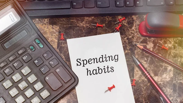 SpENDING HABITS, hesap makinesi ve ofis malzemelerinin yanındaki bir kağıt parçasına yazılmıştır.