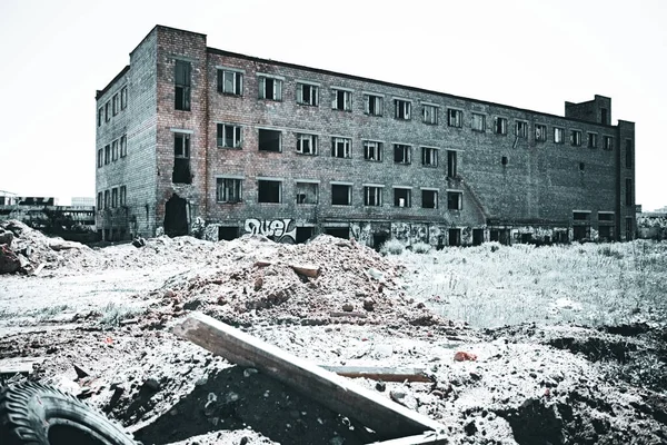 废弃的多层红砖工厂建筑 玻璃窗户碎了 独自屹立在一片废墟的田野里 一个有调的图像 — 图库照片