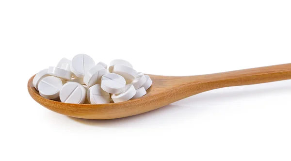 Pilules dans une cuillère en bois sur fond blanc — Photo