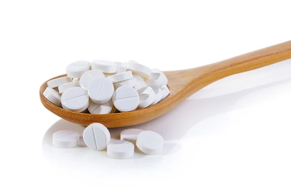 Pills in wood spoon on white background — Stock Photo, Image