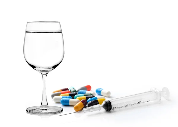 Glas water spuit en kleurrijke pil en capsules op wit — Stockfoto