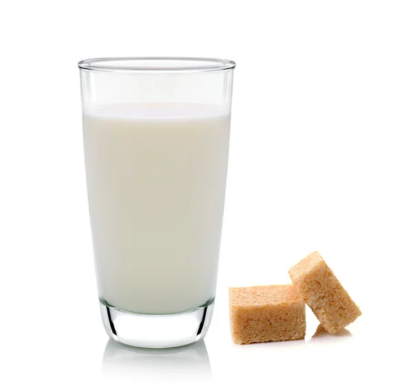 Glass of milk and cubes of cane sugar isolated on white backgrou — Stock Photo, Image