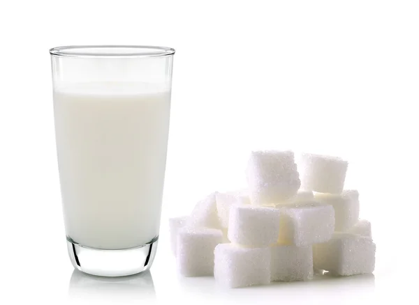 Sklenici mléka a kostky třtinového cukru izolovaných na bílém poz — Stock fotografie