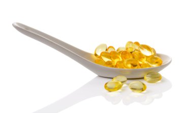 Omega 3 jel kapsül içinde kaşık beyaz arka plan üzerinde morina karaciğeri yağı