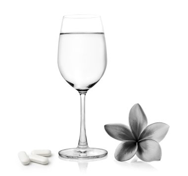 Bardak su pills ve tropik çiçekler frangipani