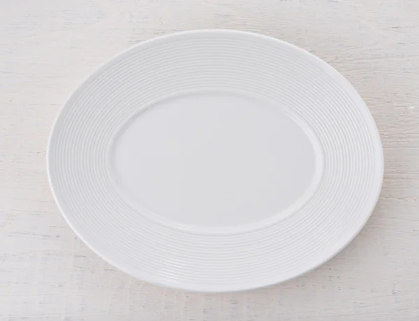 Prázdný bílý keramický talíř na dřevěném stole — Stock fotografie