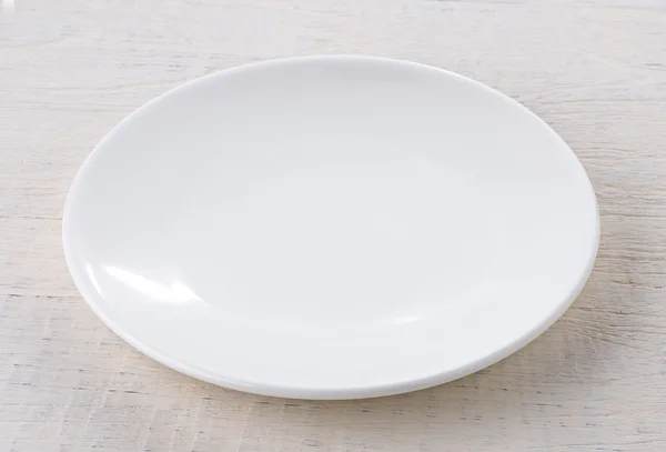 Lege witte keramische plaat op houten tafel — Stockfoto