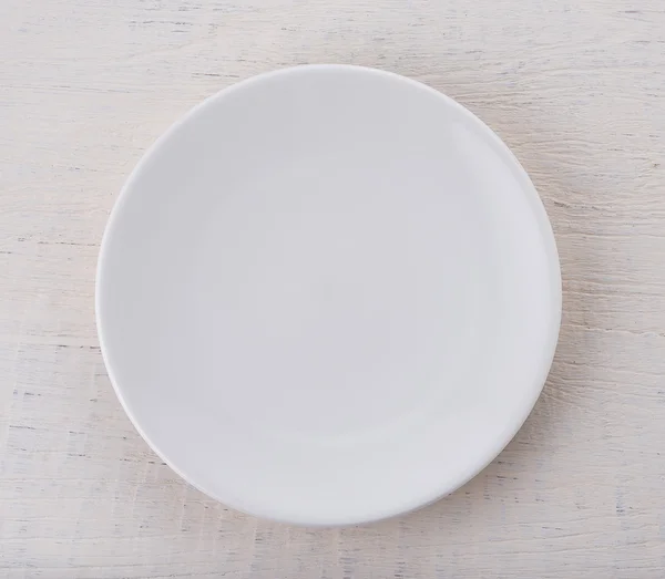 Empty white ceramic plate on wooden table