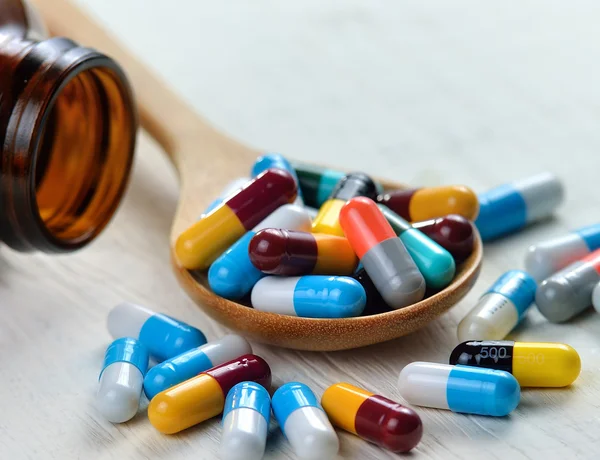 Tabletki w łyżką na białym tle drewniane — Zdjęcie stockowe