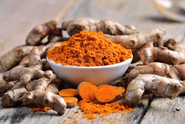 Turmeric powder in white dish on wooden background — Stock Photo, Image