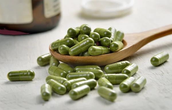 Comprimidos de cápsula de moringa na colher de madeira — Fotografia de Stock