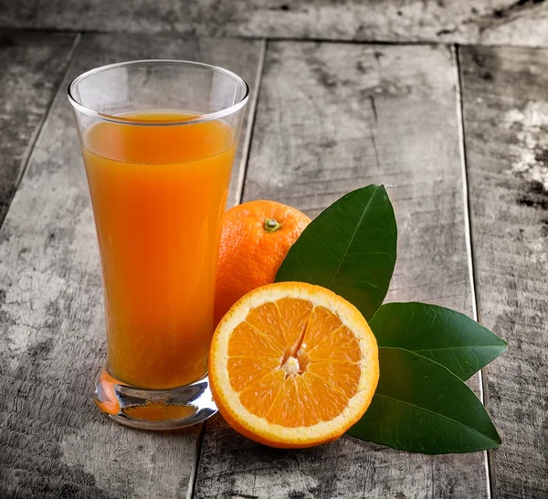 Orange juice glass and fresh oranges on wood — Stock Photo, Image