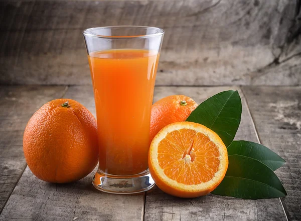 Orange juice glass and fresh oranges on wood — Stock Photo, Image