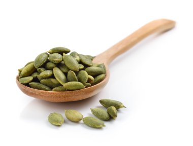 Beyaz arka planda kaşık içinde kabak tohumları