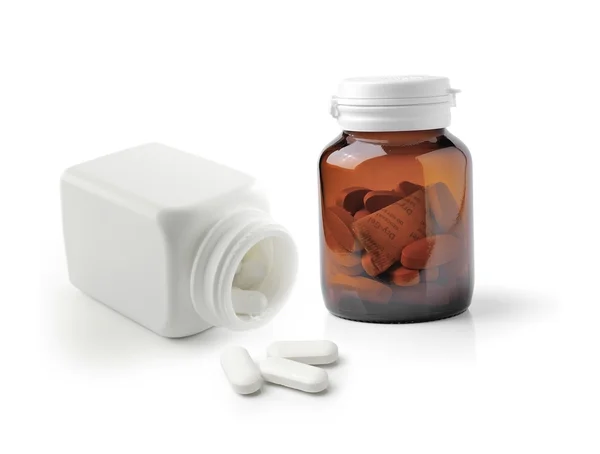Weiße Pillen und Tablettenflasche auf weißem Hintergrund — Stockfoto