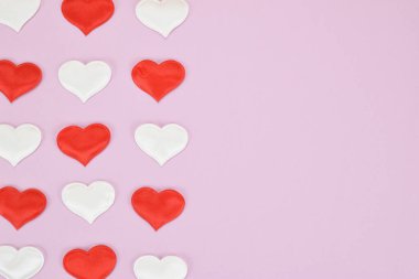 Pembe arka planda kırmızı ve beyaz kalpler, görüntünün sol tarafında üç sıra halinde dizilmiş.