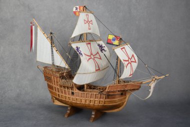 Tahta zeminde duran üç direkli yelkenli geminin koyu bir arka planda duran ahşap modelinin yan görüntüsü..