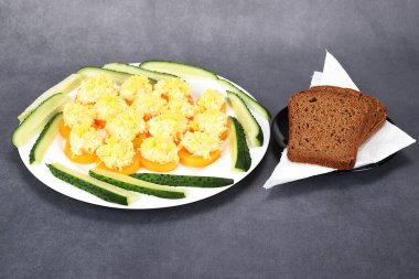 Tabağa serilmiş siyah ekmek dilimleri. Yanında domates parçalarının üzerine peynir salatası var..